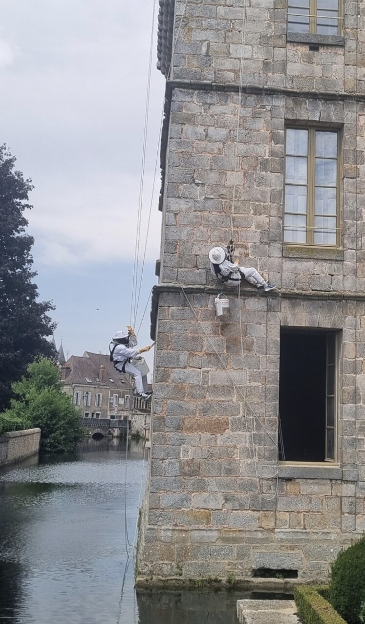 Romain Roudier et un technicien APIS en rappel sur la façade d’un château au-dessus de l’eau